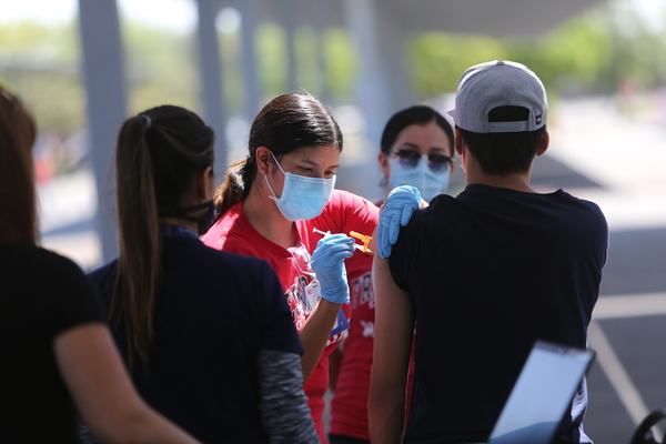 Nursing student giving COVID vaccine shot to a patient at Fresno City College parking lot.