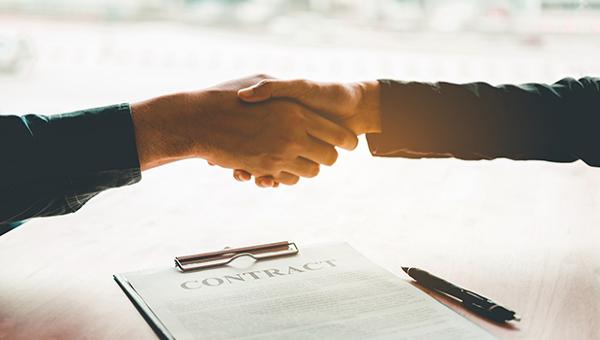 Handshake between two people over a contract. 