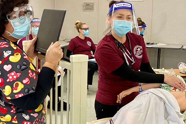 Nursing student performing an examination with instructor watching.