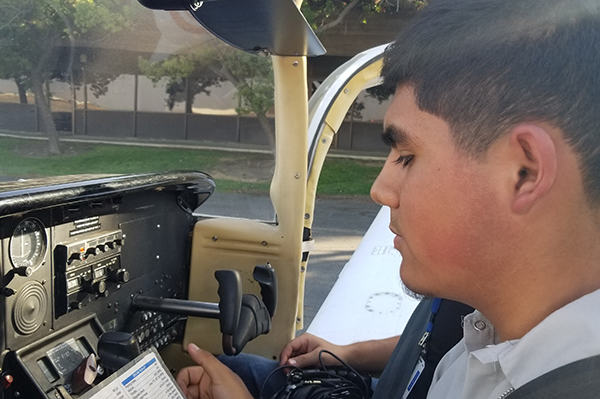 Reedley student going over pre-flight checklist inside cockpit of plane.