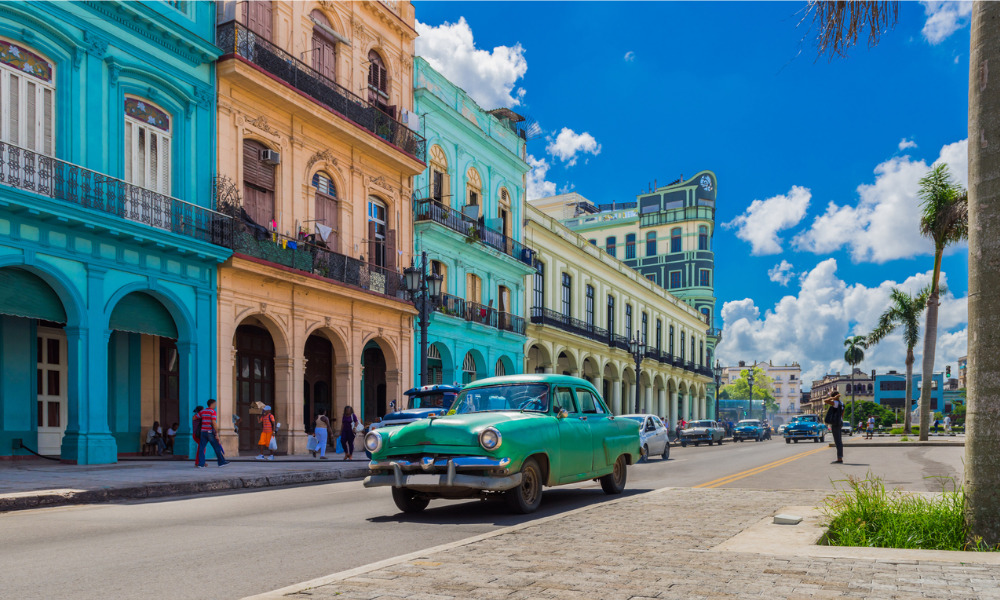 Cuban city street with colorful buildings and classic American car.