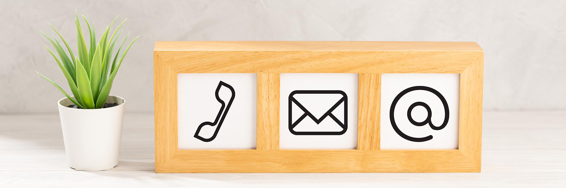 wood block with phone, email and @ symbol